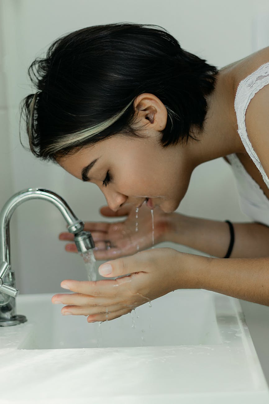 woman washing her face with water